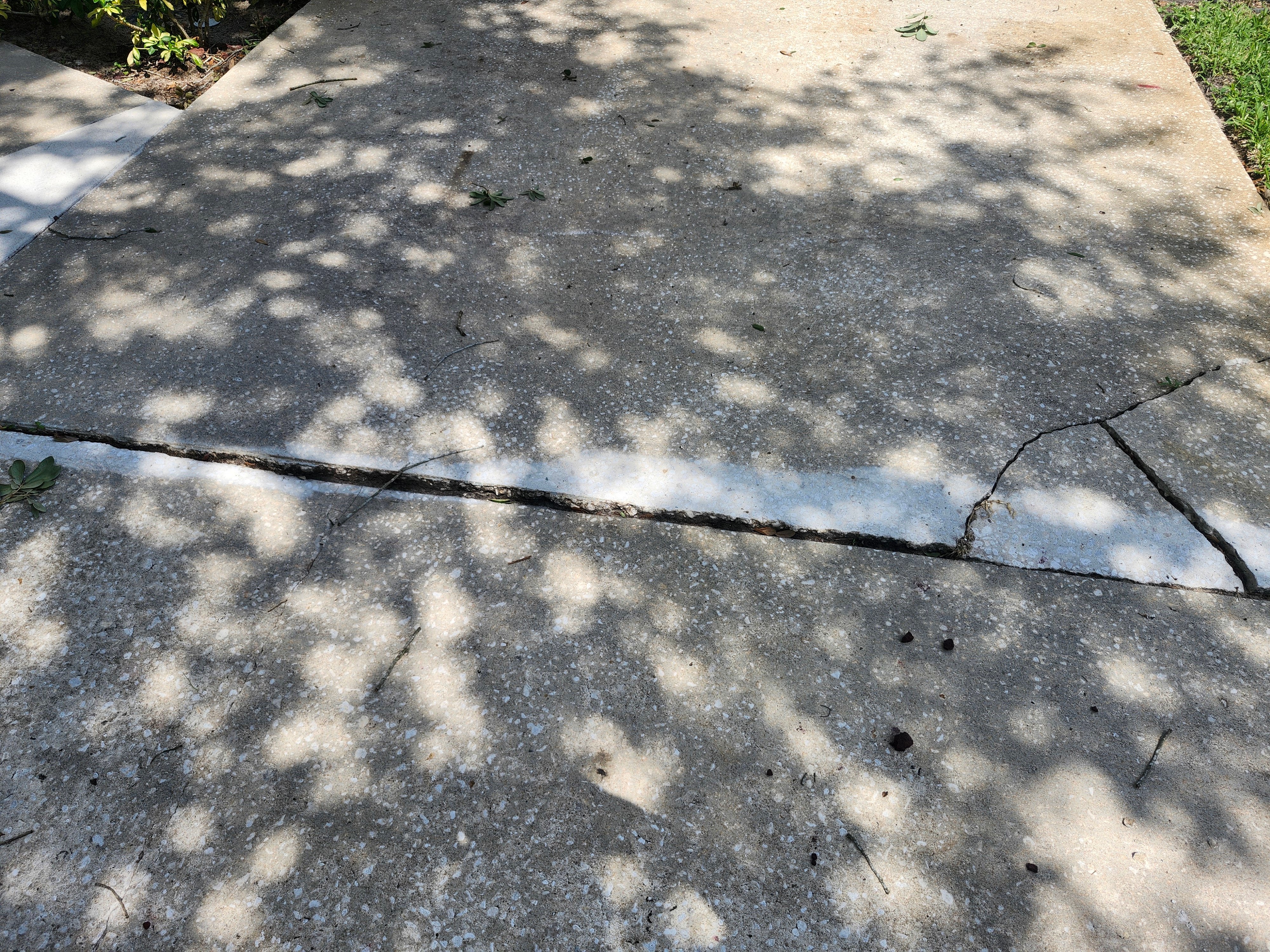 A close-up of cracked concrete creating a raised trip hazard, the kind of failure a surface patch will not fix