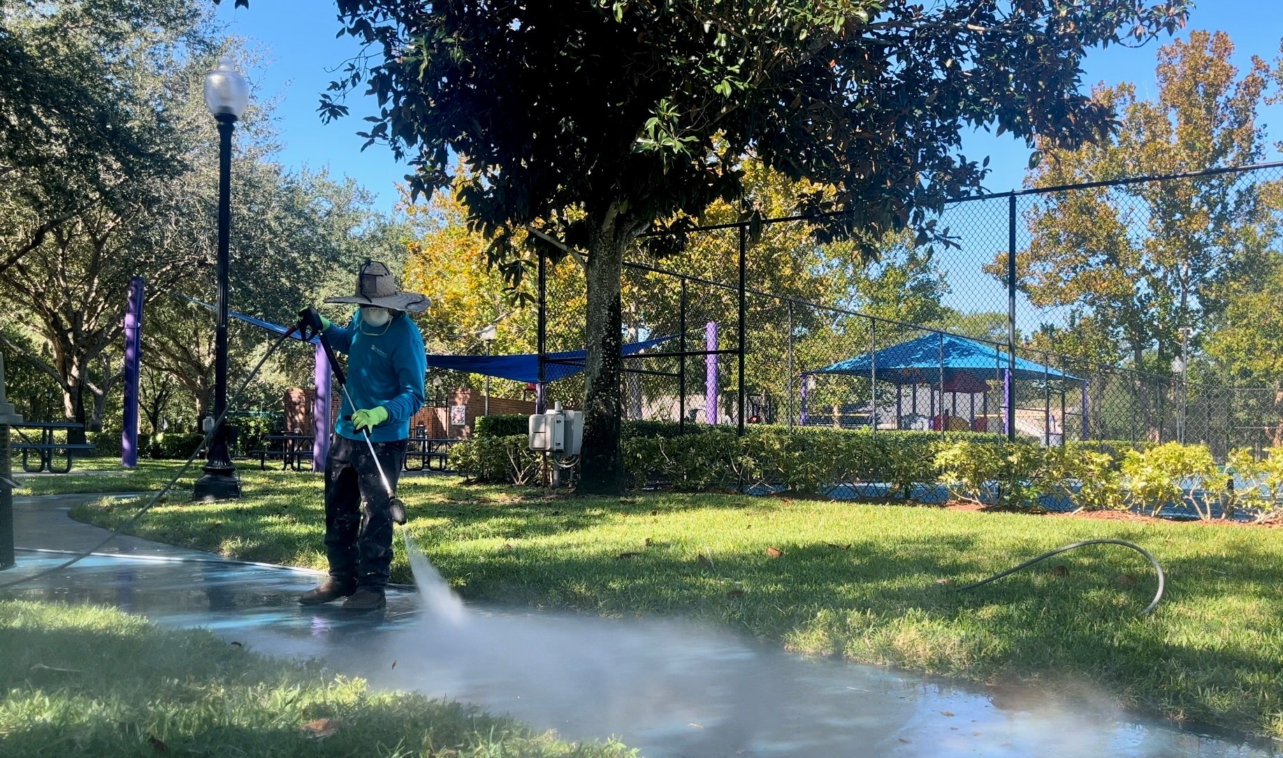 Element Service Solutions crew pressure washing a sidewalk beside community sport courts.