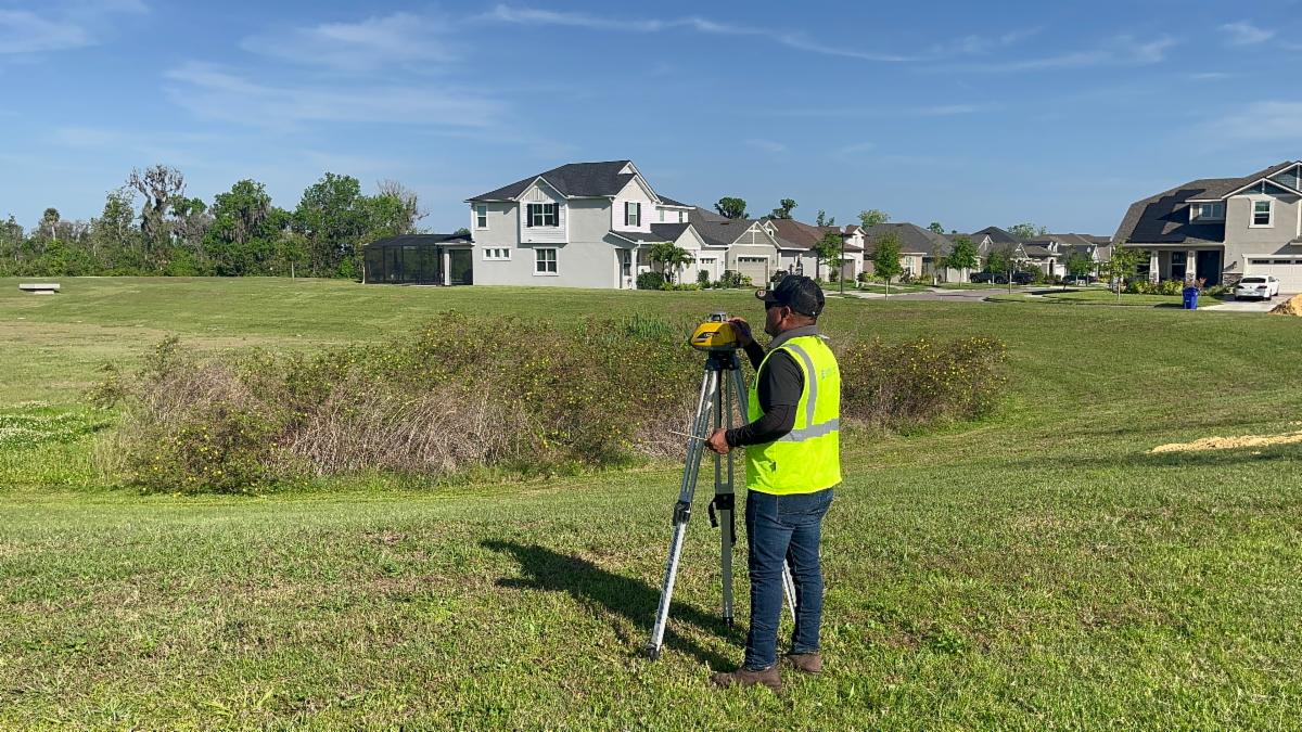 Element Service Solutions crew member surveying a community drainage site
